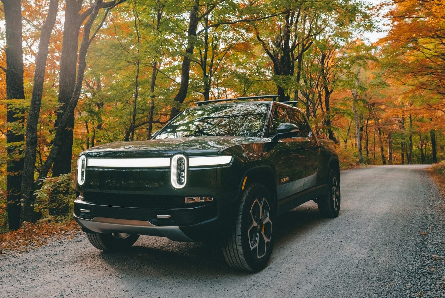 a black car parked on a road surrounded by trees
